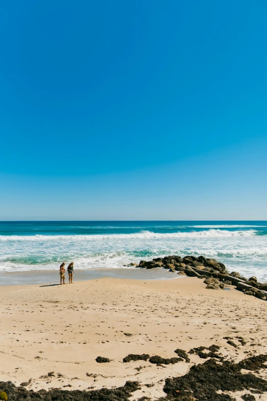 people standing on the sand next to the ocean