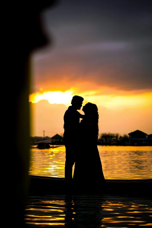 two people stand on the shore during sunset