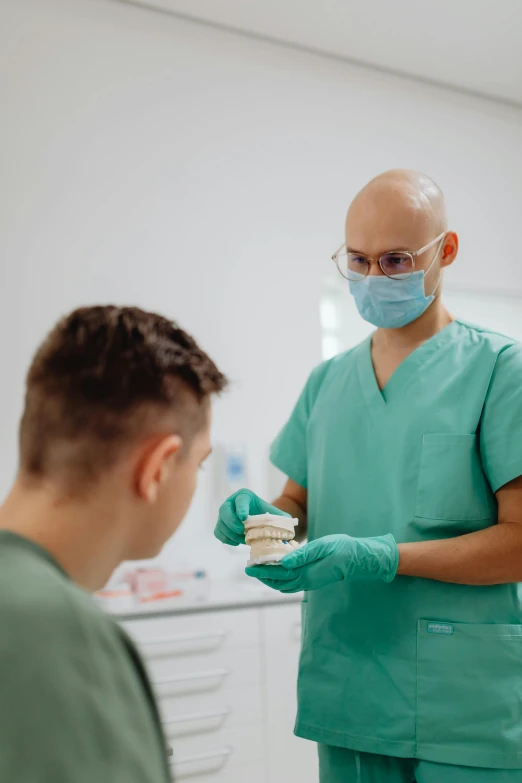 a dentist standing next to an adult surgeon holding a cake