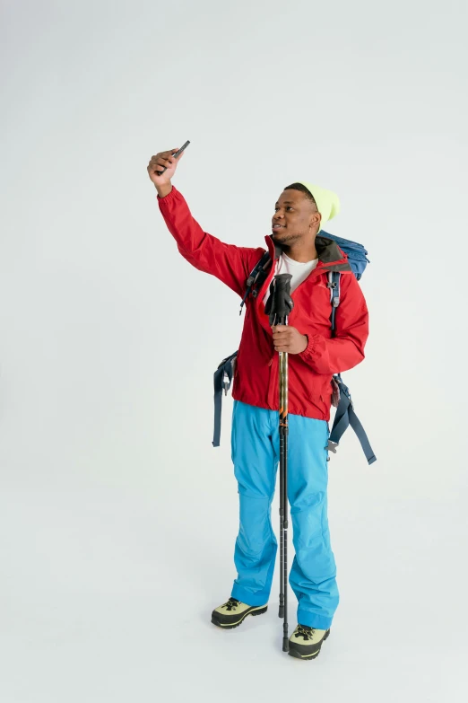 a man stands holding a ski poles and wearing a bright red jacket