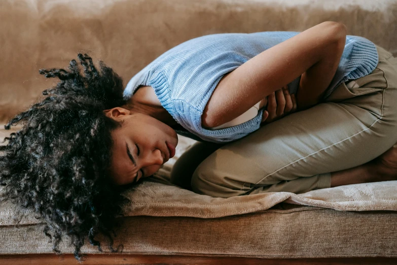 a girl is sleeping on a brown sofa