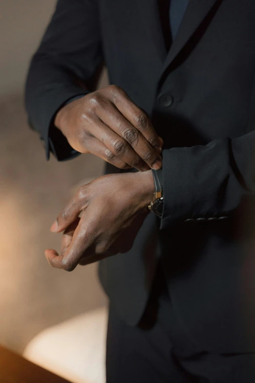 the person wearing a suit holds his wrist