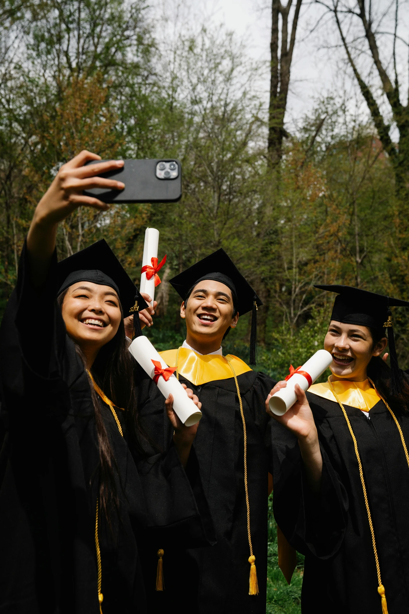 three graduates pose for a po with one holding a diploma