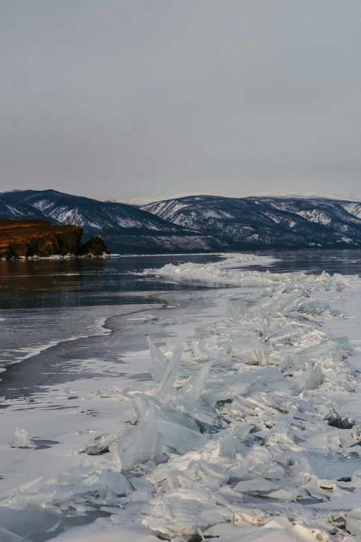 snow on a lake during the winter with mountains in the background