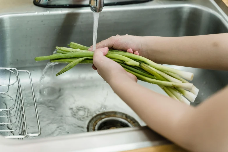 a person washing their food in the sink