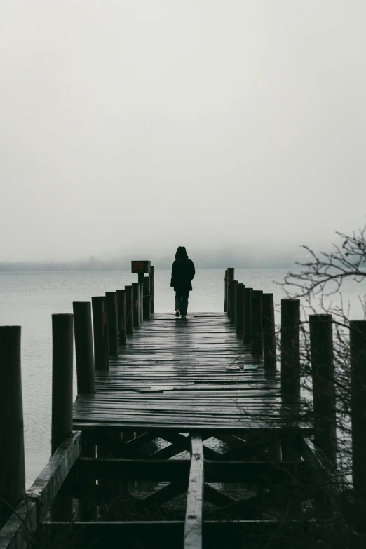 man on a dock watching the ocean during an overcast day