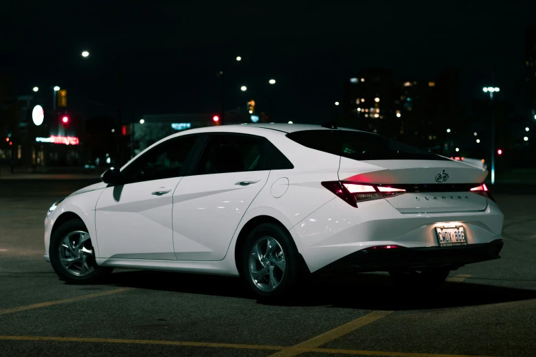 an all white car on a city street at night