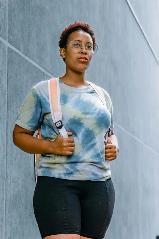 a woman stands by a building with her legs crossed