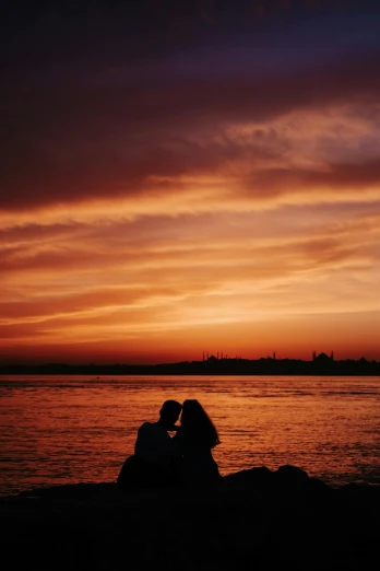 a couple sitting next to each other in front of a body of water