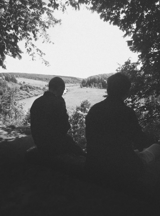 two people are sitting and looking out over water
