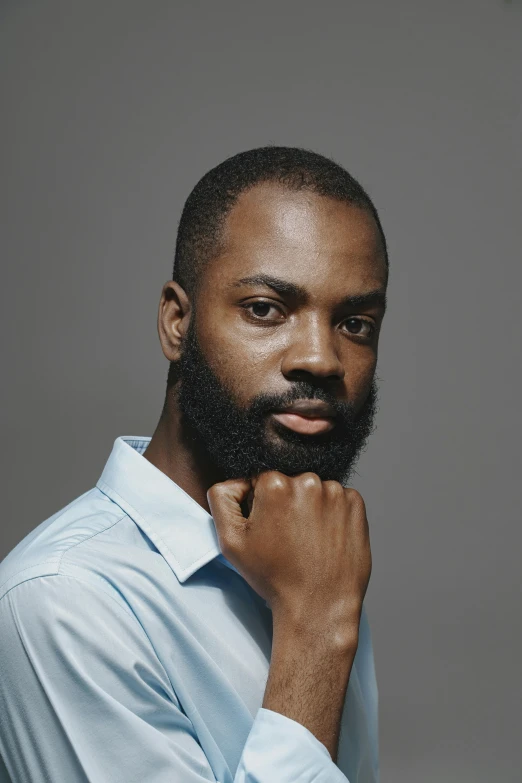 a black man with a beard and white shirt looking away from the camera