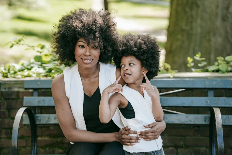 an adult and child sitting on a park bench