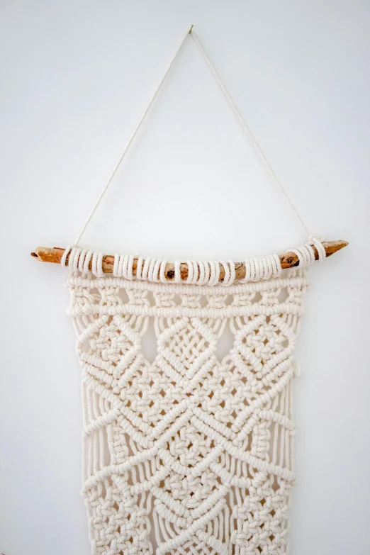 a white macrame hangs from a wall