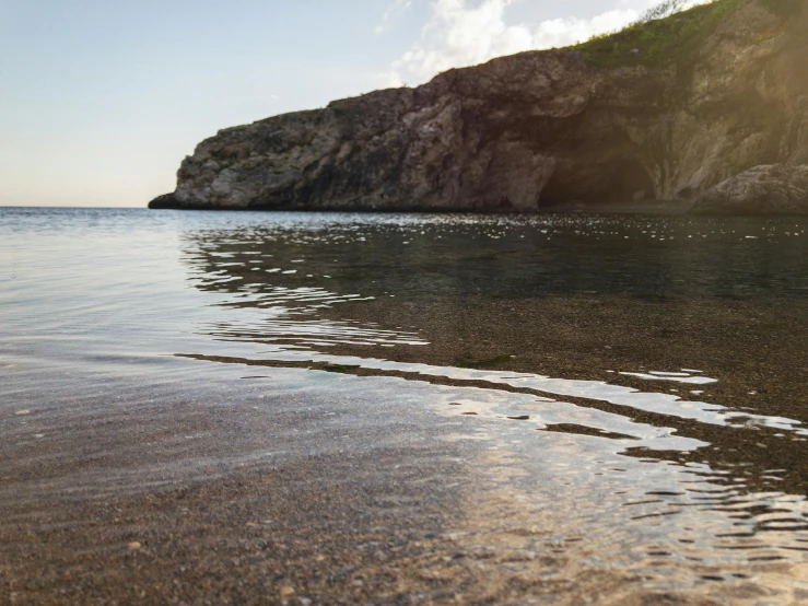 the ocean with a rock face on the shore