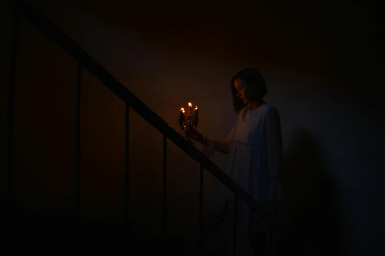 a woman that is holding a candle in her hand