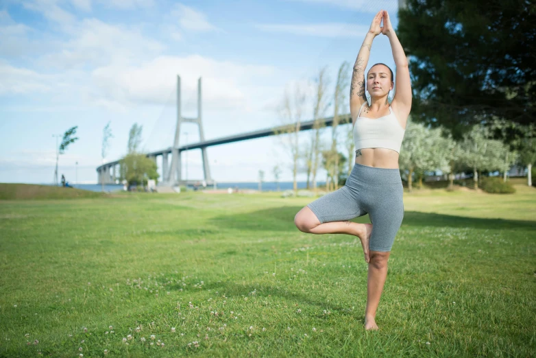 a woman is standing in the grass doing yoga