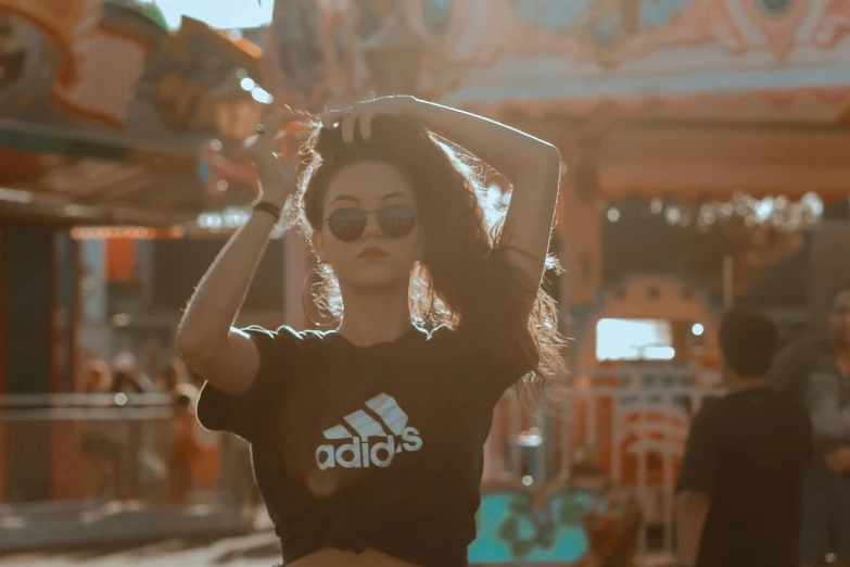 woman dancing in the sun with sunglasses and a black t - shirt