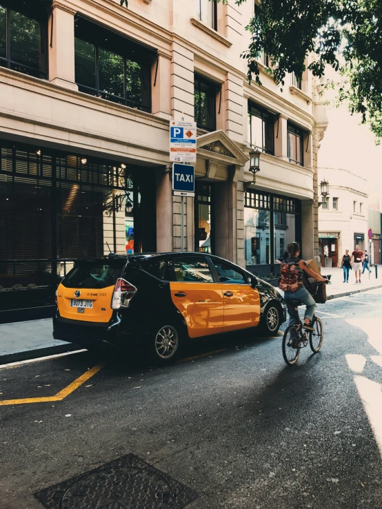 there is a man that is riding his bike next to a taxi