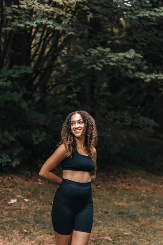 a smiling black woman in high waisted shorts and sports  top