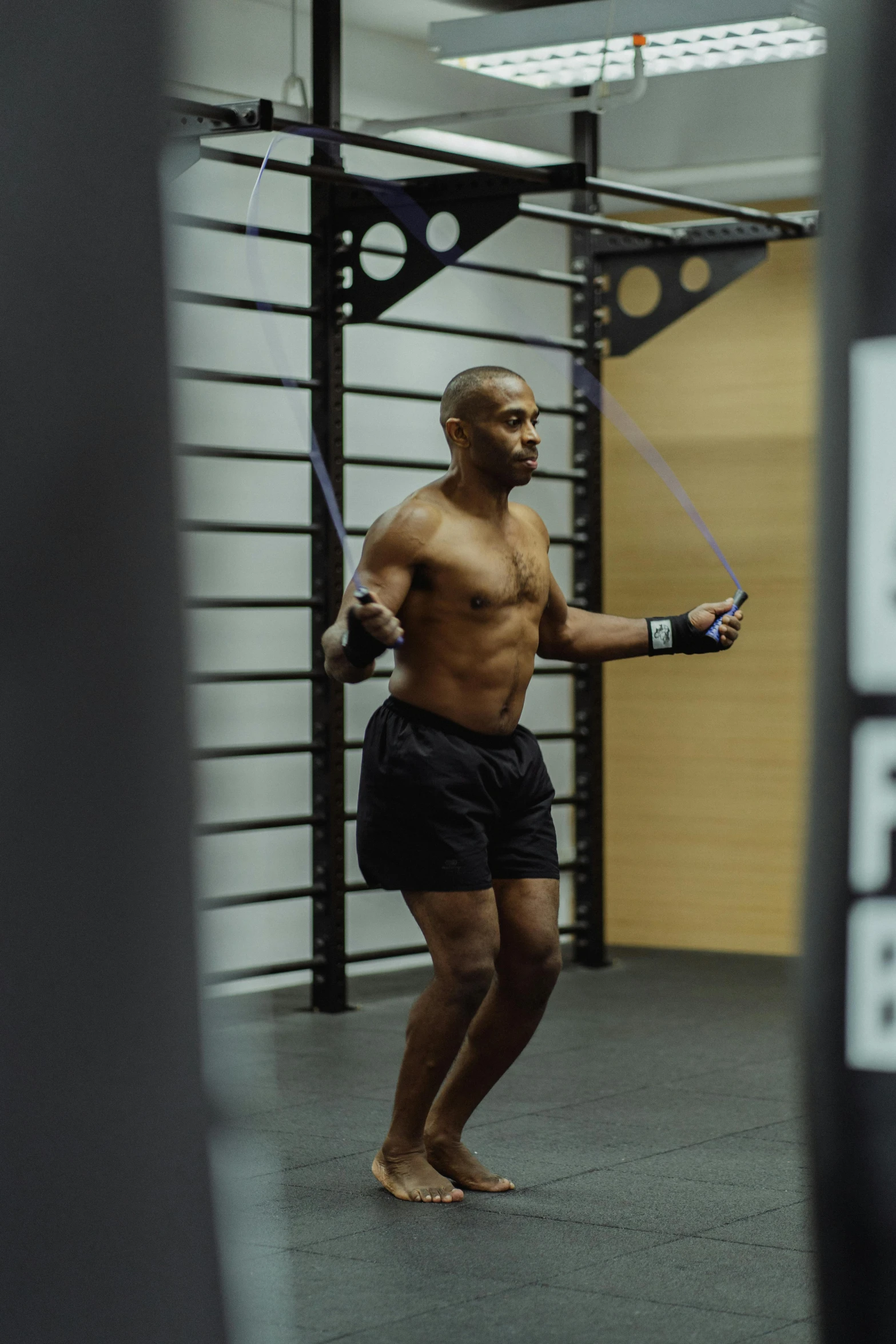 a shirtless man is holding a pair of skipping ropes