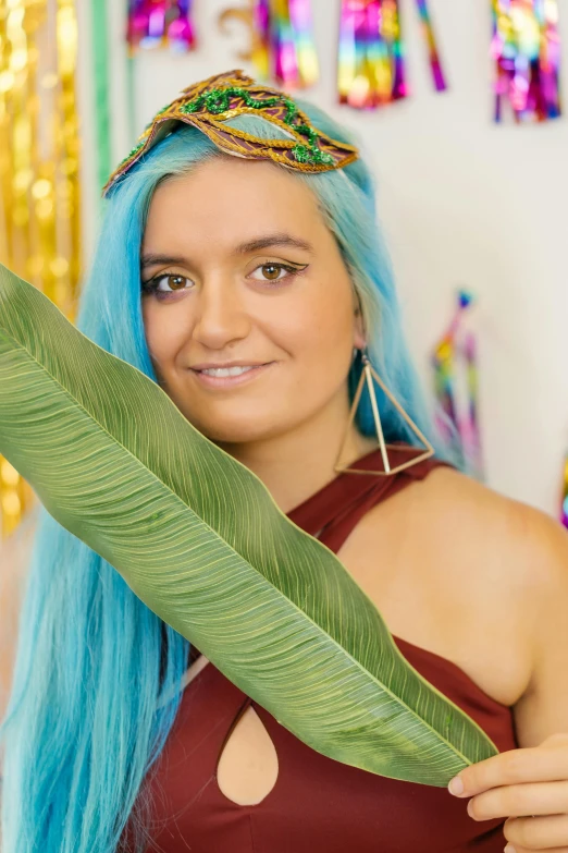 a woman with blue hair is posing with a leaf