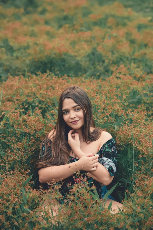 a woman is sitting in the grass in a field