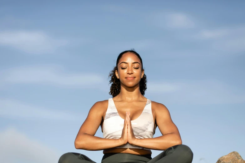 woman meditating on grass on sunny day