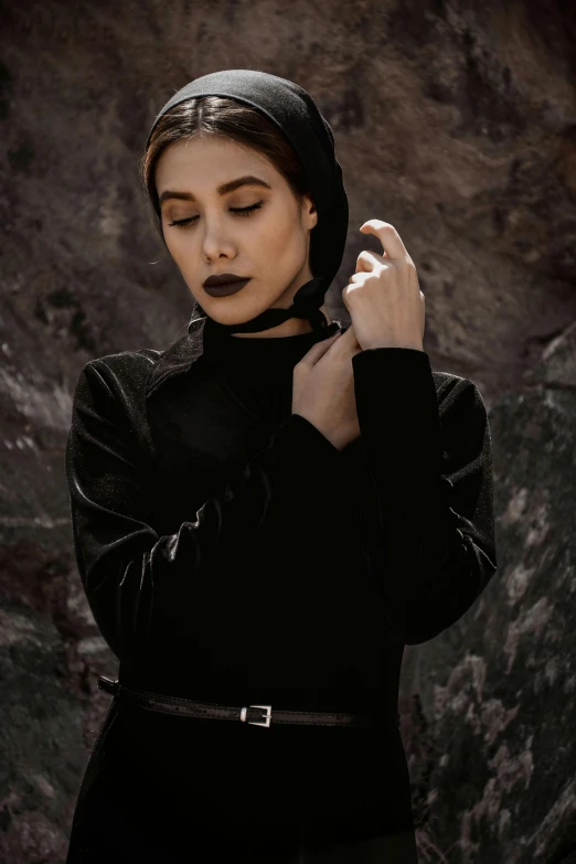 woman dressed in black poses with eyes closed