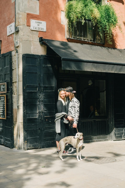 two people walking a dog on the sidewalk