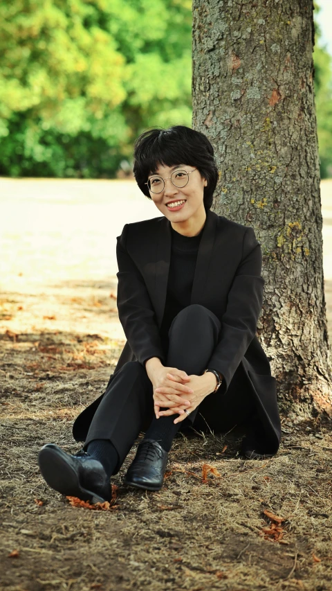 a woman sitting in the grass under a tree