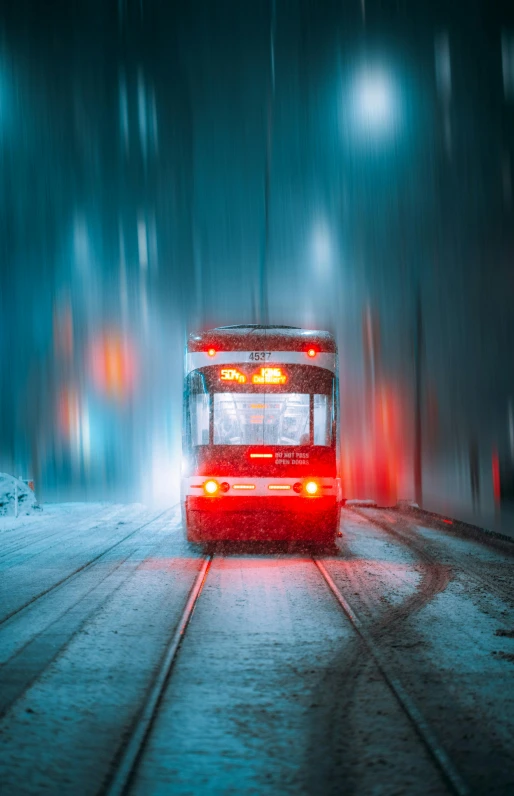 red bus driving down snow covered roadway during the day