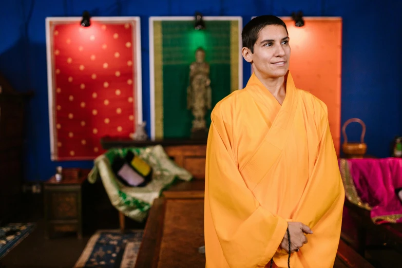 a smiling young man in a robe at the front of an empty room