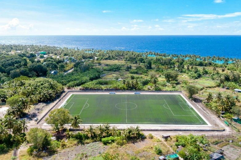 an overhead s of a tennis court with the ocean behind it