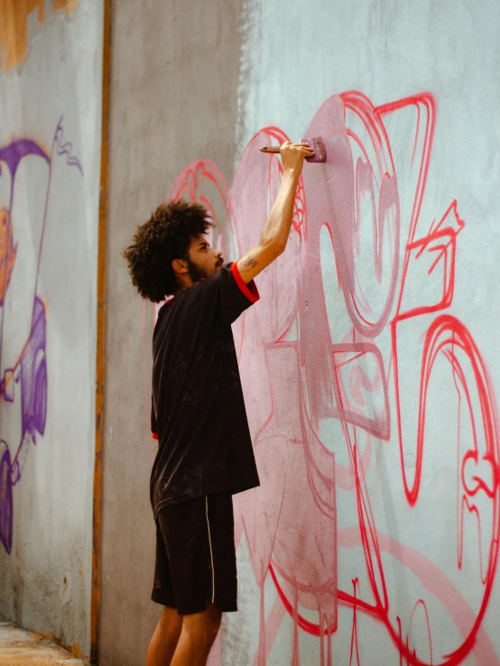 man with brush in hand painting graffiti on wall