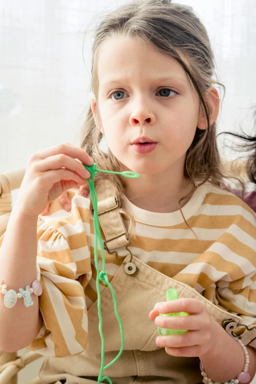 a child is holding a green string and has a surprised look