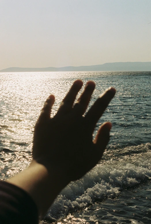 someone is reaching out toward the waves on a sunny day