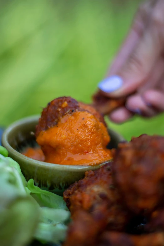 a hand dipping soing from a bowl into a salad