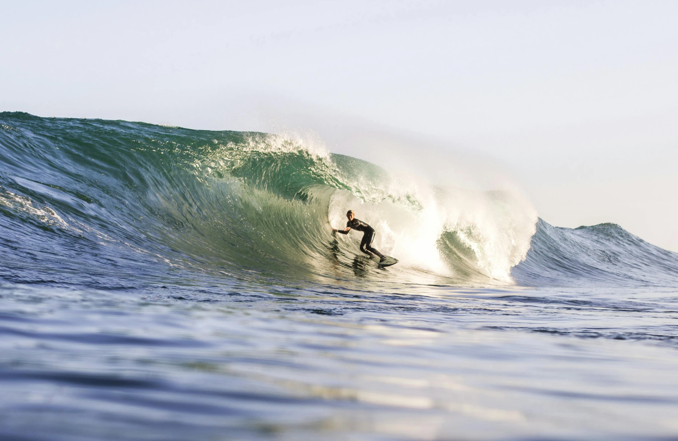 surfer riding huge breaking ocean wave on clear day