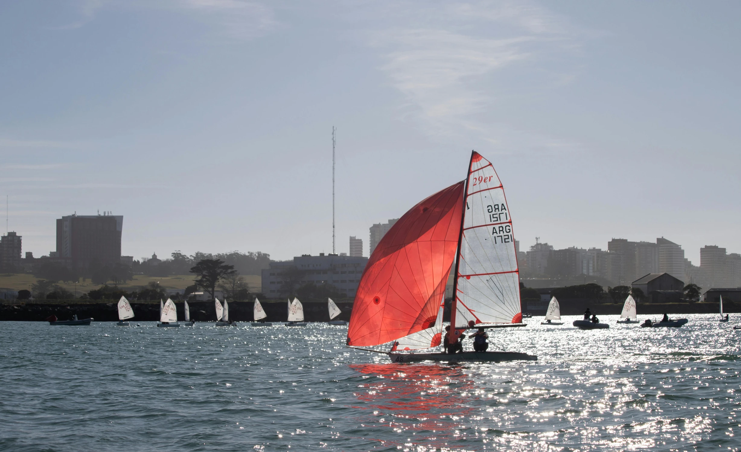 people riding on top of sail boats on a large body of water