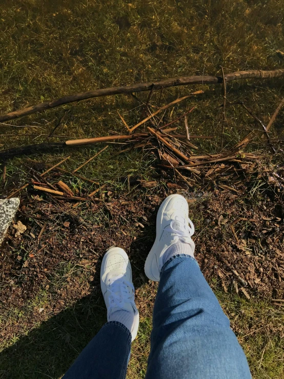 the legs of a person standing on the grass near the water