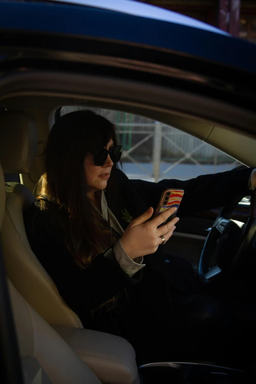 a woman sits in her car and looks at the phone