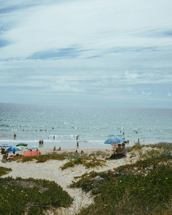 people at the beach with their umbrellas out