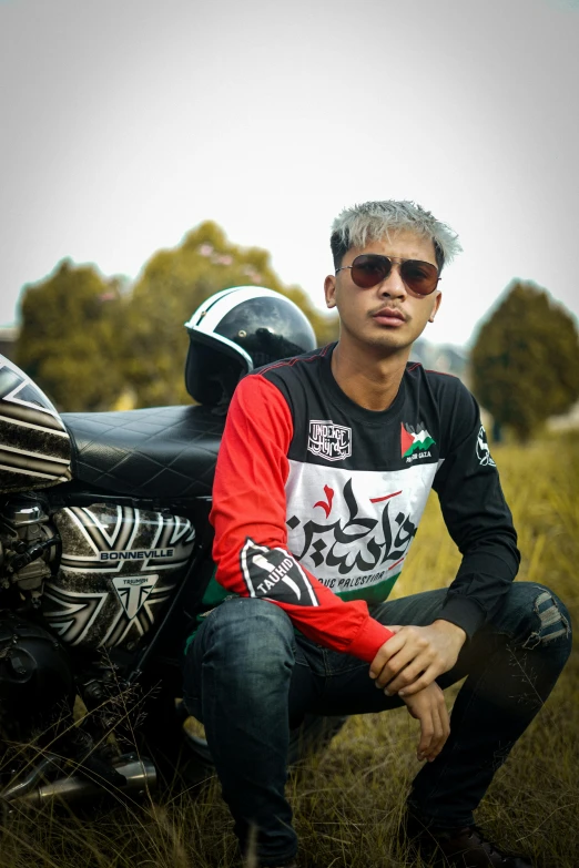 a person posing with his motorcycle and wearing sunglasses