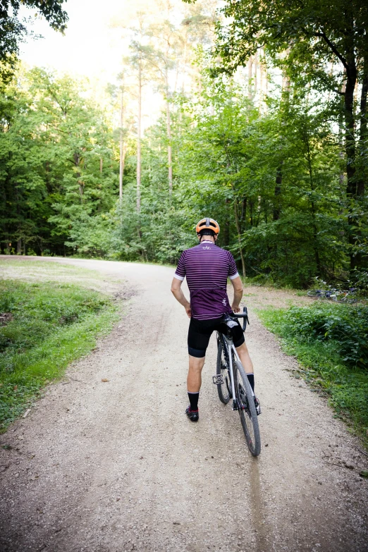 a man in striped shirt on bike down dirt road