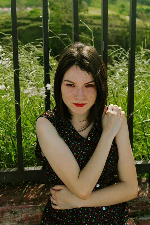 a girl with her hands crossed, wearing a black floral shirt