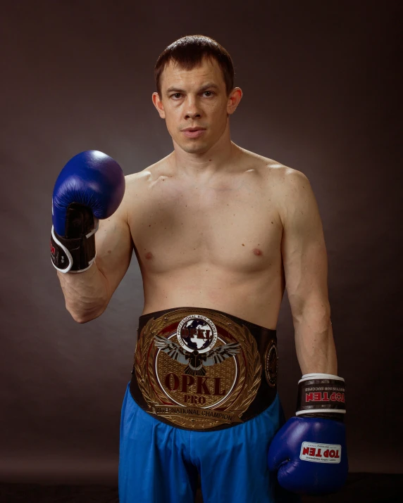 a shirtless young man poses with boxing gloves