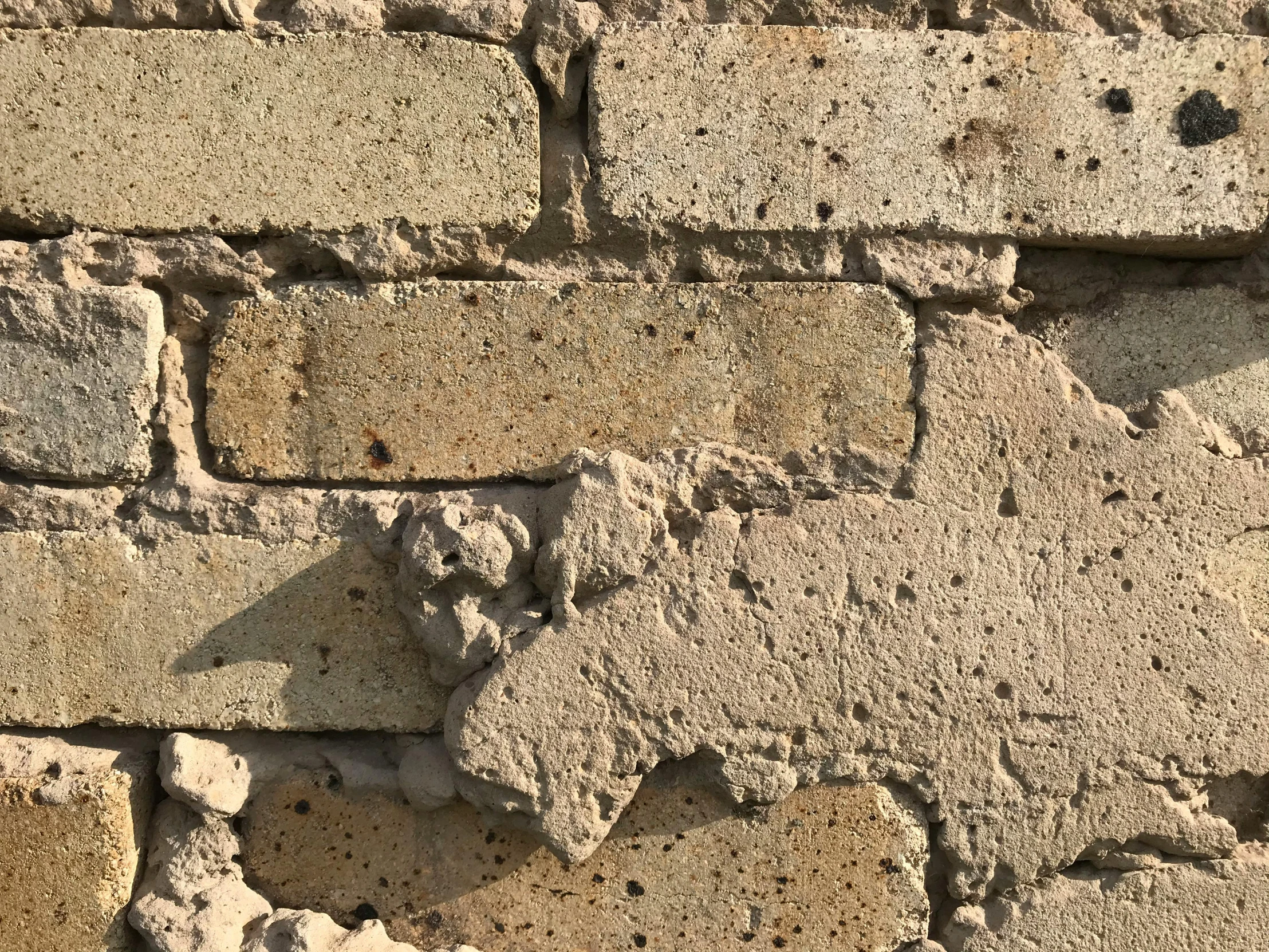 a white fire hydrant is next to a wall made of bricks