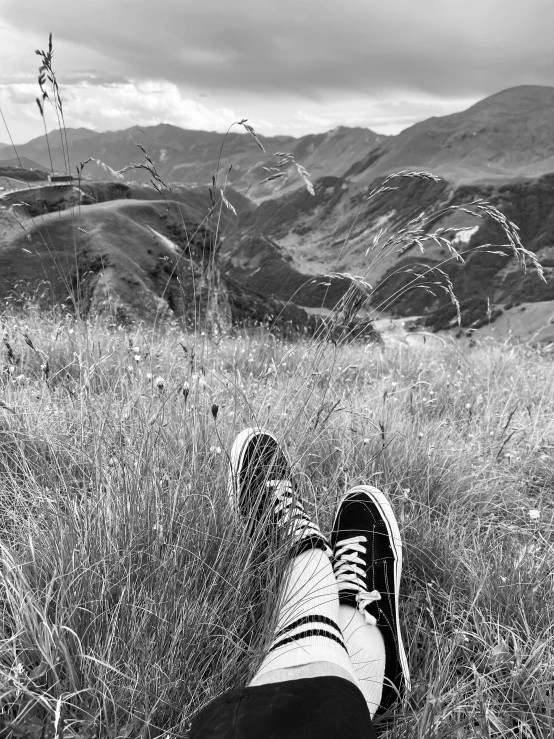 a person with their shoes off sitting in the grass on a hill