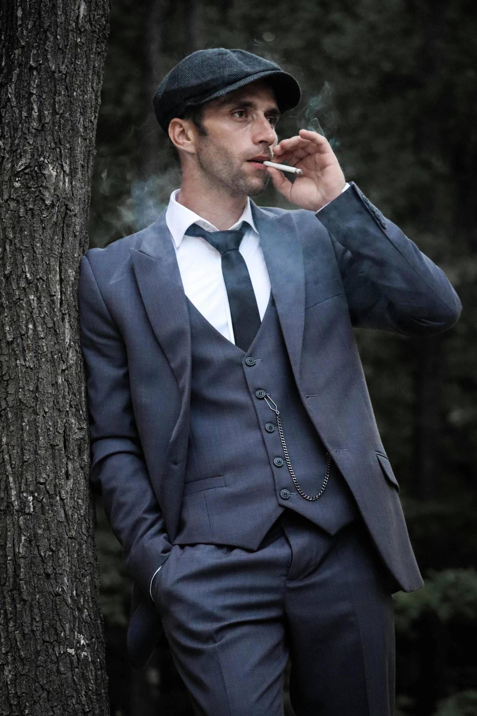 a man dressed in a gray suit smoking cigarette
