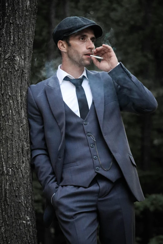 a man dressed in a gray suit smoking cigarette